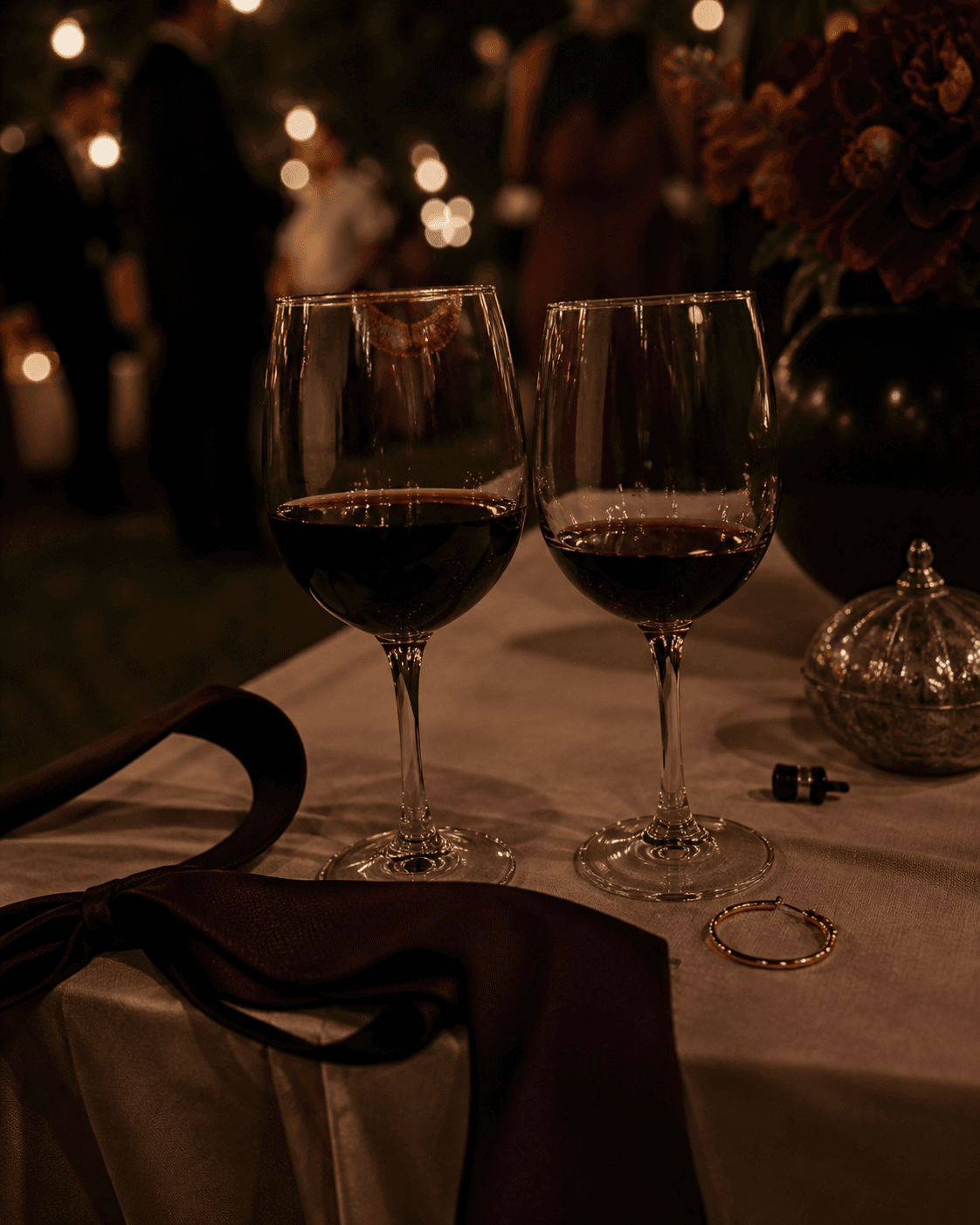 Dos copas de vino, una marca de labial, una corbata y un pendiente después de una fiesta familiar.